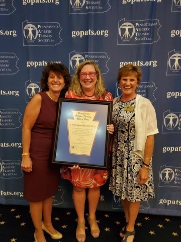 Three people standing together holding an award. 