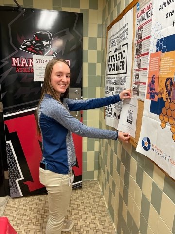 Kasey Creech looking at a paper on a bulletin board. 