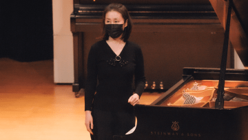 A woman standing near a piano. 