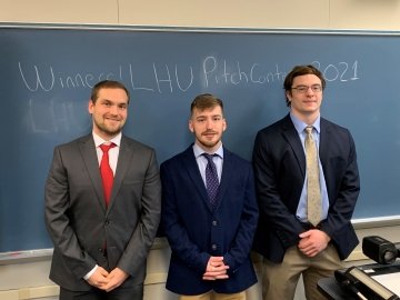 Three people standing in front of a chalkboard. 