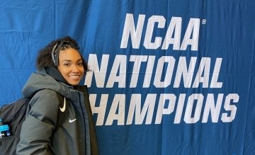 Riyana Owens standing next to a NCAA National Champions sign. 