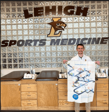 A man standing in front of a Lehigh Sports Medicine sign. 