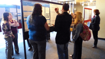 A group of people looking at an information board. 