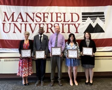 A group standing side by side with awards. 