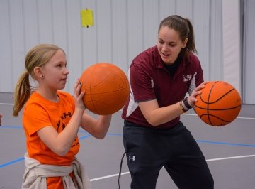 A Health and Physical Education student at CU-Lock Haven teaches basketball handling techniques to a young child