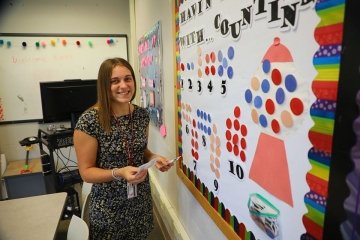 An Early Childhood Education major at CU-Mansfield in front of a classroom bulletin board about counting