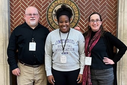 Three people standing together for a picture. 