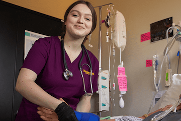 Nursing student holding sim patient's arm