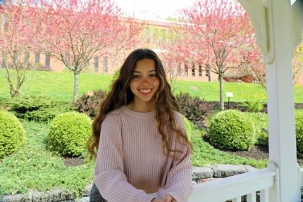 Student posing for a photo on a pergola