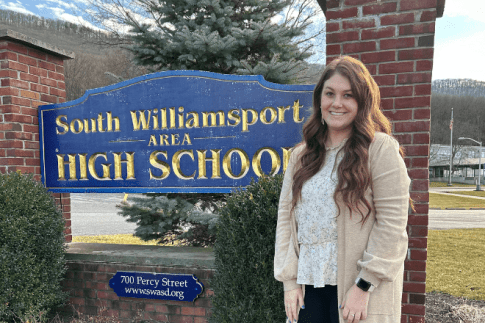 Mallee Hornberger standing in front of South Williamsport Area High School smiling