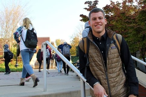 Commonwealth University - Bloomsburg student Derek Berger leans on a handrail while students walk behind him