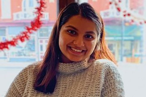 Sneha Patel smiling at camera, wearing a grey sweater.