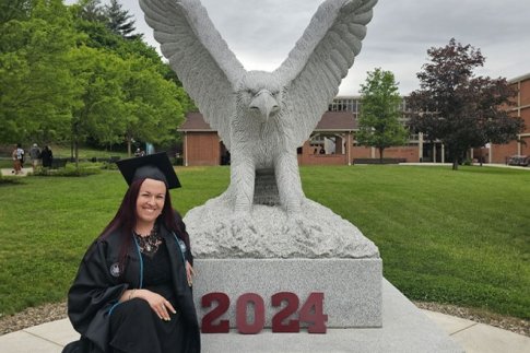 Tiffany Sims sitting by eagle statue after commencement at CU-Lock Haven.