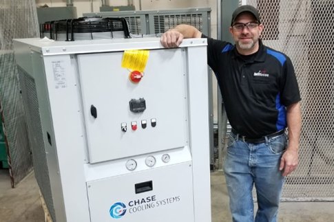 Tommy Kane at work standing next to a HVAC system.