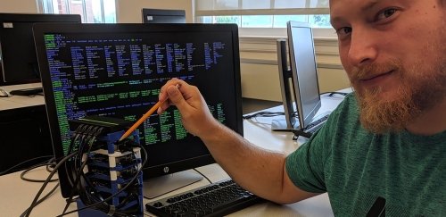 Male Computer Science student uses pencil to point to networking project at Commonwealth University - Bloomsburg.