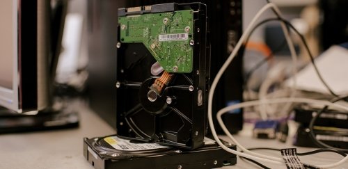 Computer hard drives stacked on a desk with other peripherals and cables.