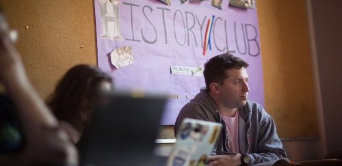 Students in front of history club bulletin board during a meeting