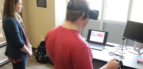 a student with virtual reality glasses on working with another student