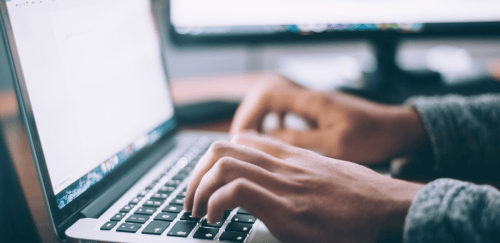 a close up of hands typing on a macbook computer