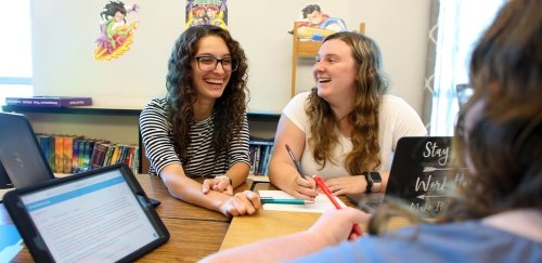 two students laughing working in a classroom