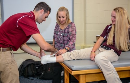 A student observing how to wrap an ankle injury