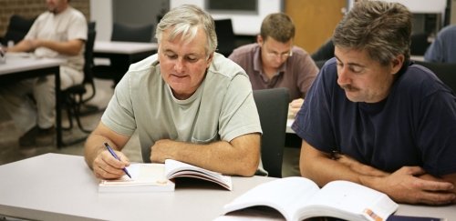 Adult students study from books in Workforce Development training course at Commonwealth University.