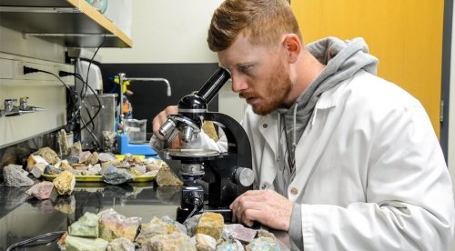 Commonwealth University geology student using microscope to study rocks