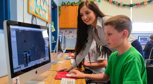 Female student teacher assists student with computer application