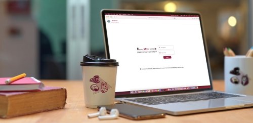 Laptop computer displaying MyHousing Self-Service next to a coffee mug, iPhone and AirPods.