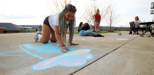 Mansfield student drawing with chalk outside