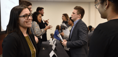 A group of Commonwealth alumni speak to several students at a student professional development event.