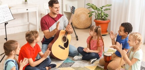 Music teacher claps as he instructs young students