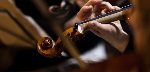 Hand of a musician playing the violin in an orchestra close-up