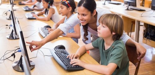 Teacher instructing elementary students in computer class