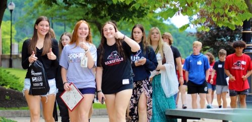 Students giving a big thumbs up while walking at Mansfield's campus during orientation 