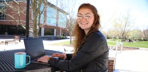 M.S. Information Technology Student sitting at a table working on a lap top