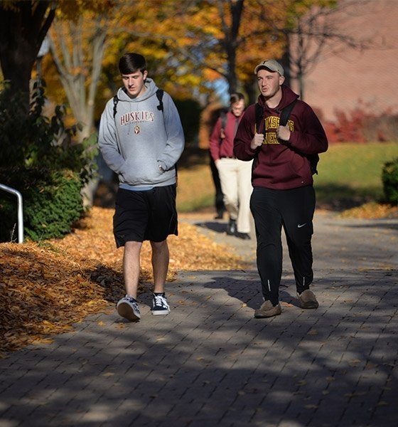 Two male students walk along path during the fall at Commonwealth University - Bloomsburg.