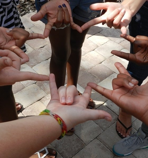 Hands in huddle making sign