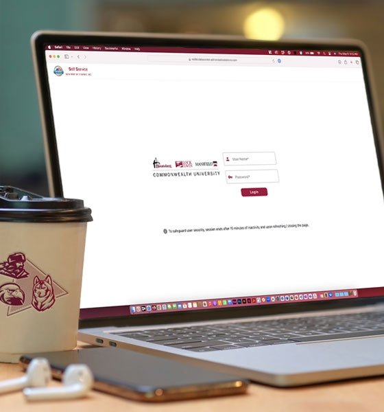 Laptop computer displaying MyHousing Self-Service next to a coffee mug, iPhone and AirPods.