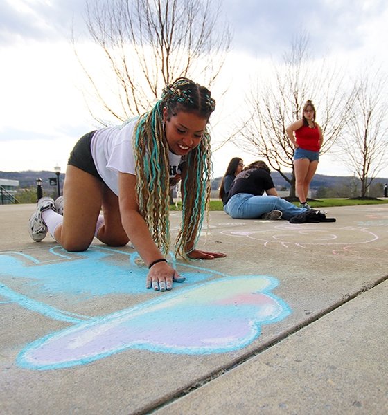 Students draw chalk art in front of their residence hall at Commonwealth University-Mansfield, formerly Mansfield University.