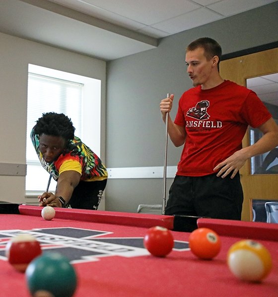 Roommates play a fun game of pool at their residence hall at Commonwealth University-Mansfield, formerly Mansfield University.