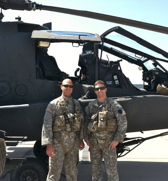 Two soldiers pose in front of helicopter