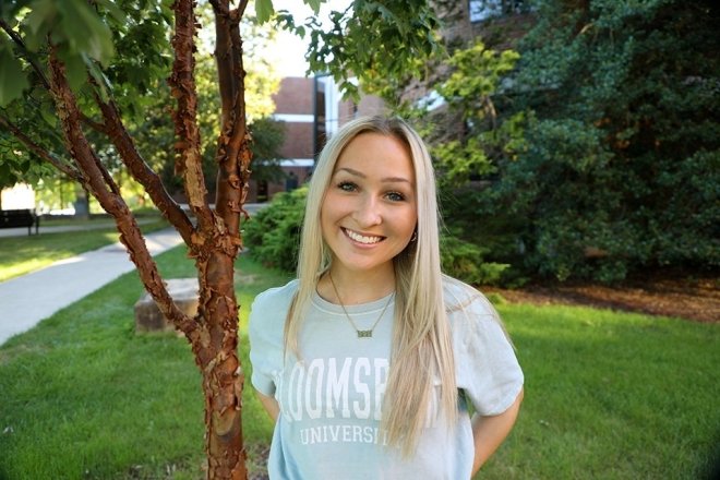 A girl standing by a tree. 