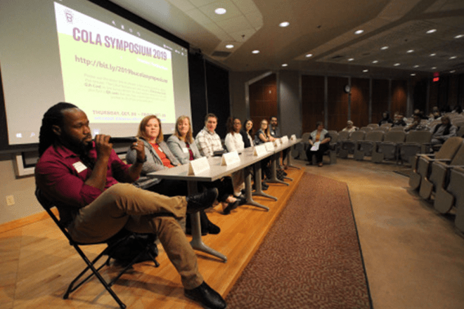 A group of people sitting at tables on a stage. 