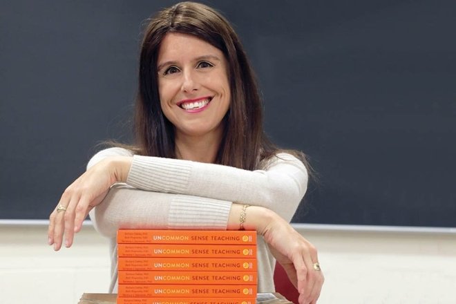 A woman leaning on stacked books. 