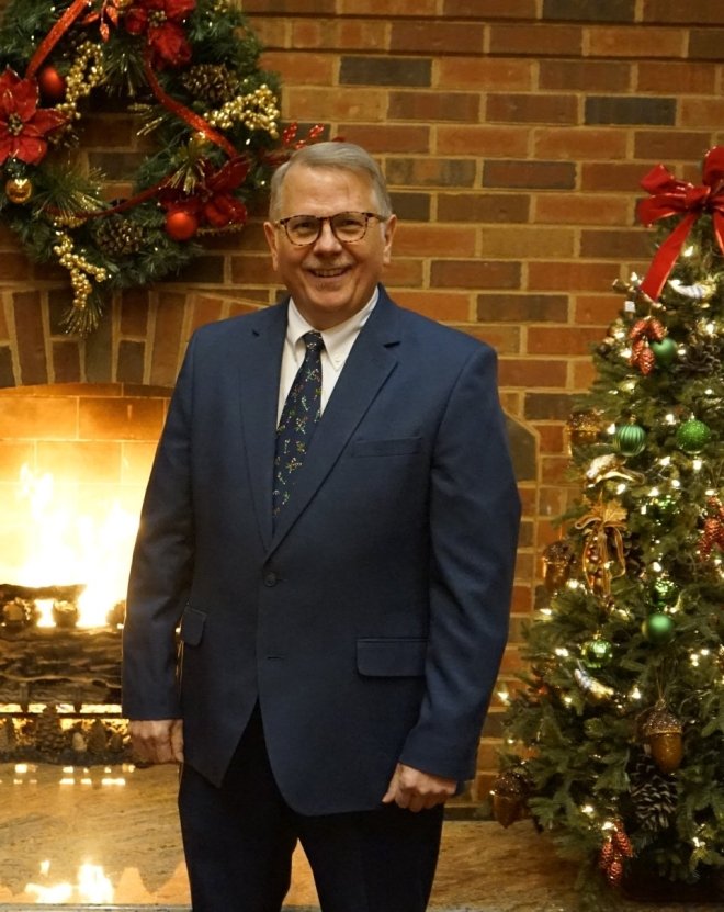Philip Burlingame wearing a suit in front of a fireplace. 