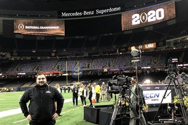 Matt Mastrogiovanni ’17 standing in football field stadium, smiling.