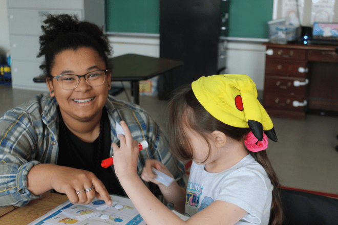 A New Story teacher laughs as she assists a student with a project