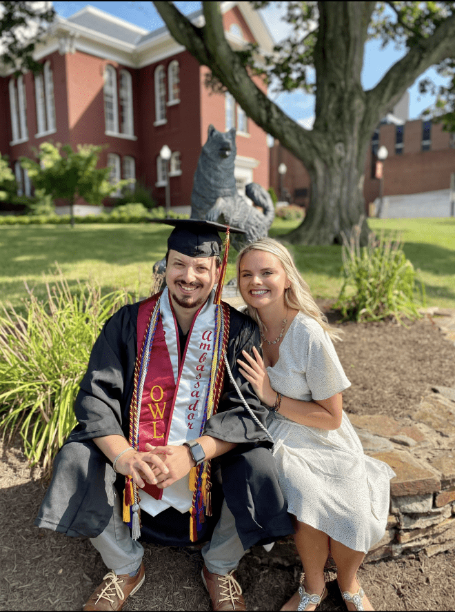 Cole Neff '20 (left) sits in front of the Husky statue with his wife.