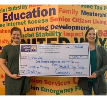 Two people holding a large check. 